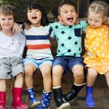 Group of kindergarten kids friends arm around sitting and smiling fun