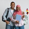 Cheerful african american muslim students couple holding german flag