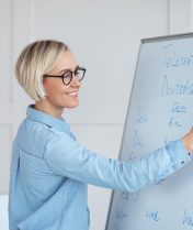 Happy young German tutor writing grammar rules on blackboard, giving online lesson from home